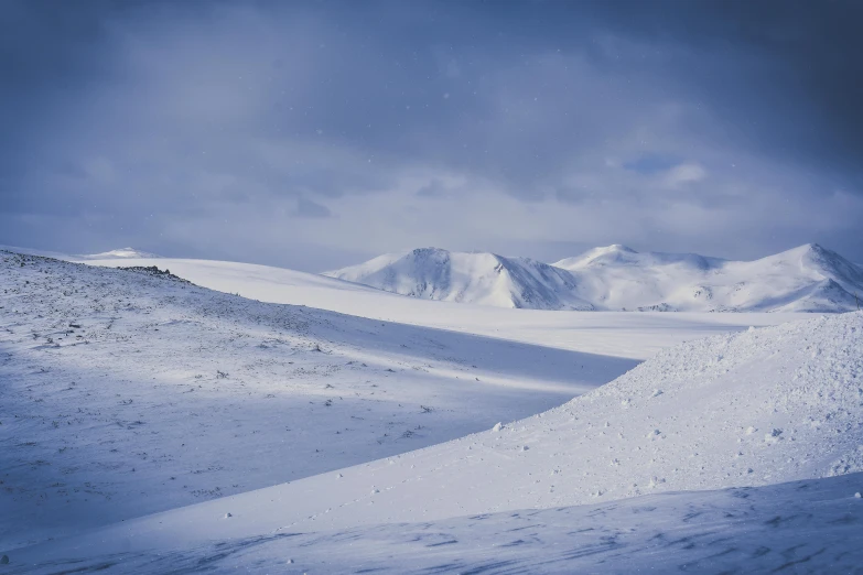 a man riding a snowboard down a snow covered slope, by Hallsteinn Sigurðsson, hurufiyya, hasselblad photography, distant mountain range, white and blue, 1 4 5 0