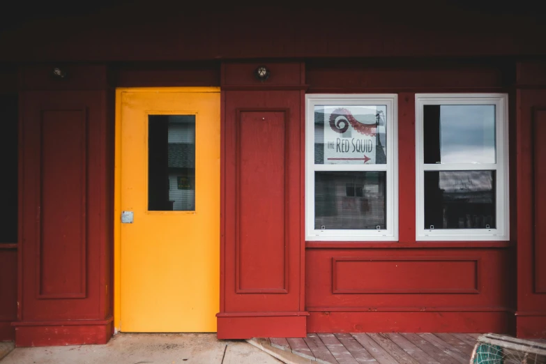 a red building with a yellow door and windows, by Jessie Algie, pexels contest winner, fan favorite, small hipster coffee shop, red brown and white color scheme, red and obsidian neon