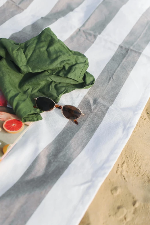 a plate of fruit sitting on top of a beach towel, at a beach, on the ocean