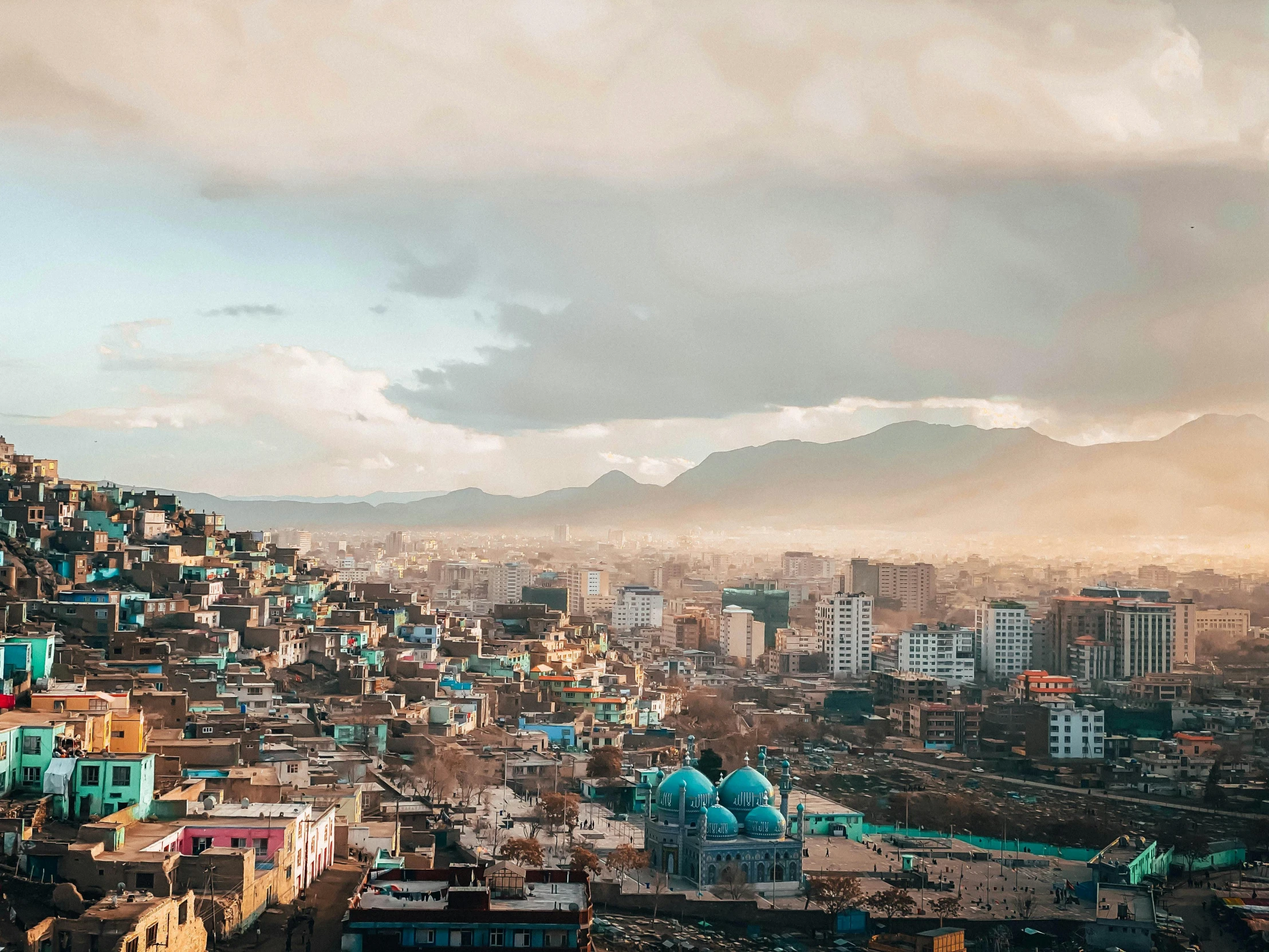 a view of a city from the top of a hill, a colorized photo, pexels contest winner, an afghan male type, slide show, background image, ash thorp khyzyl saleem