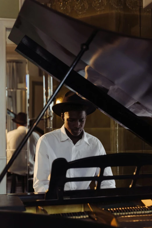 a man standing next to a piano in a room, unsplash, harlem renaissance, white suit and hat, ( ( theatrical ) ), dark skinned, farming