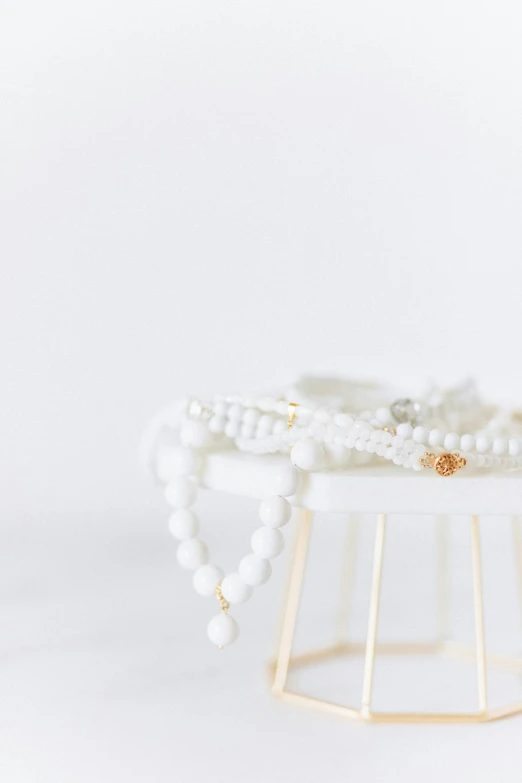 a close up of a bracelet on a stand, by Nicolette Macnamara, unsplash, minimalism, white with gold accents, beads of sweat, stacked, white cloud