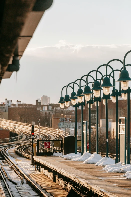 a train station with snow on the ground, by William Berra, trending on unsplash, art nouveau, light fixtures, harlem, skyline showing, seaside