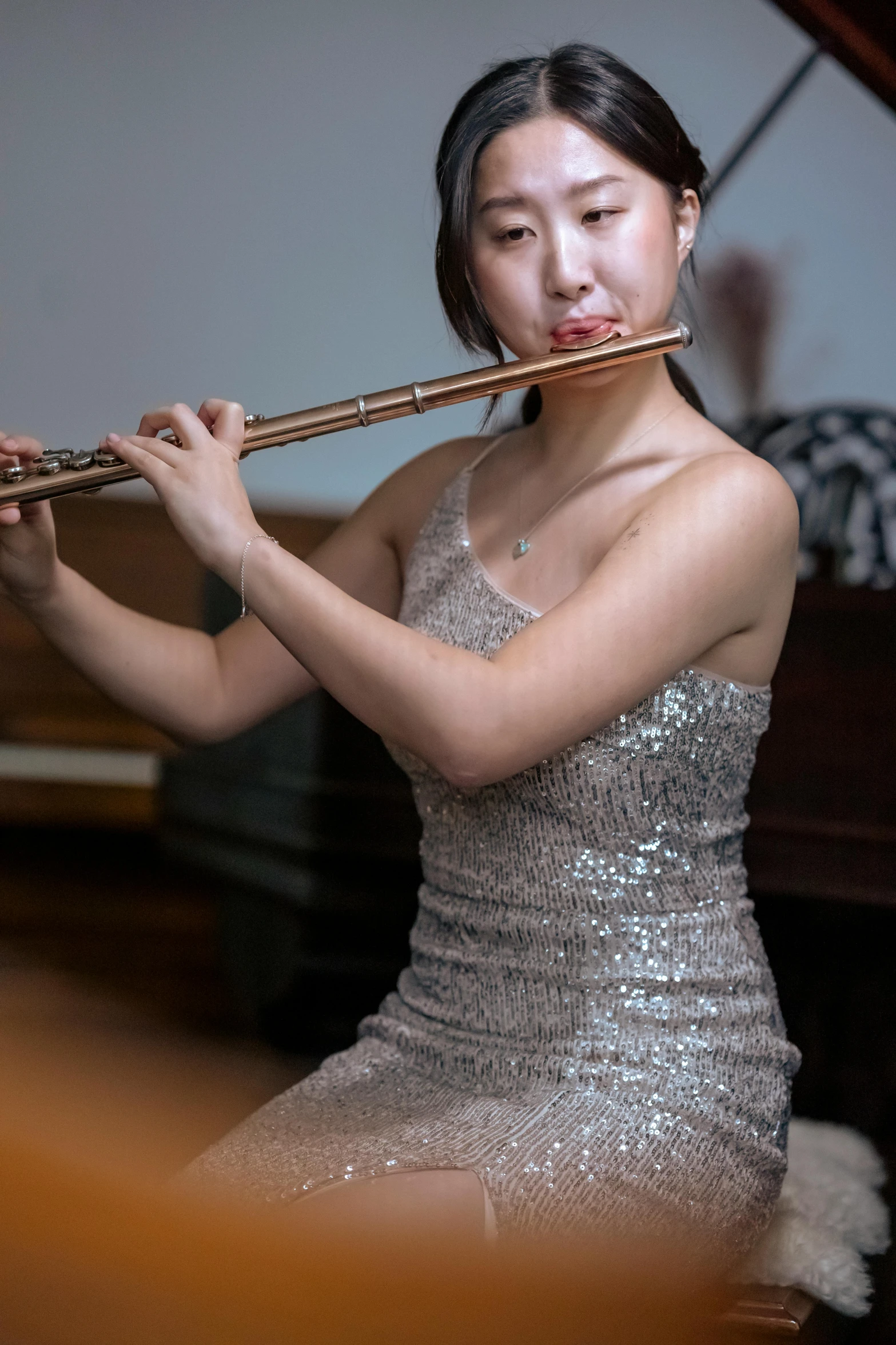 a woman in a silver dress playing a flute, inspired by Zheng Xie, unsplash, portait image, yanjun chengt, low quality photo, brown