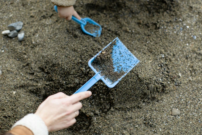 a person digging in the sand with a shovel, by Julia Pishtar, plasticien, blue-black, handheld, thumbnail, brown