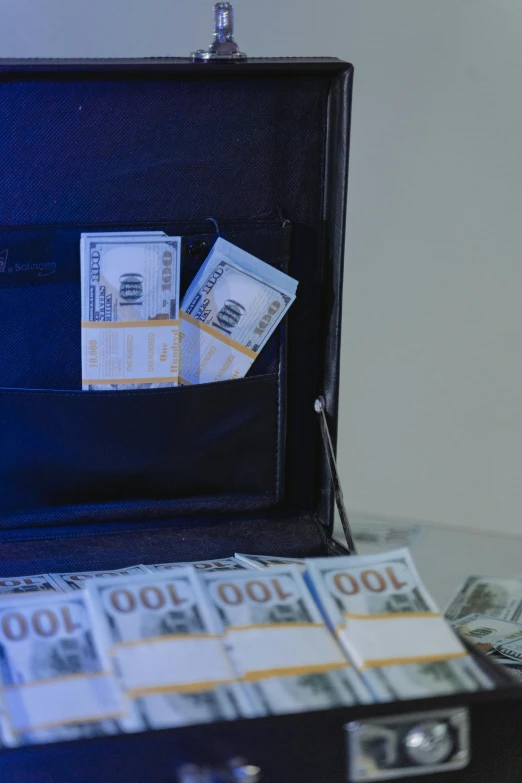 a suitcase filled with money sitting on top of a table, slide show, multiple stories, underexposed, thumbnail