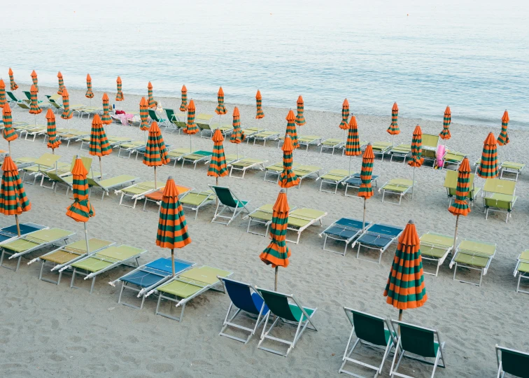 a number of lawn chairs and umbrellas on a beach, by Giorgio De Vincenzi, unsplash contest winner, hyperrealism, orange neon stripes, italian mediterranean city, cone shaped, woman