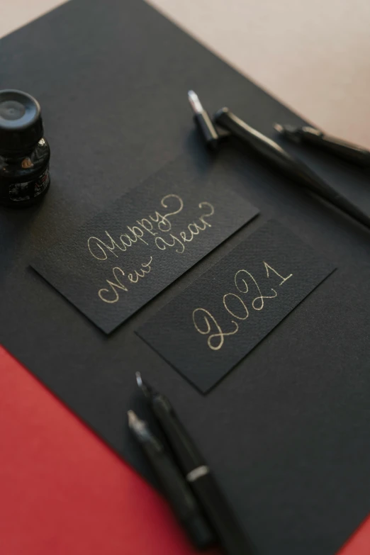 a pen sitting on top of a notebook next to a pair of scissors, trending on unsplash, happening, new years eve, “modern calligraphy art, business card, thumbnail