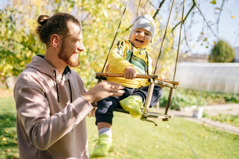 a man holding a small child on a swing, pexels contest winner, in the garden, avatar image, kacper niepokolczycki, guide