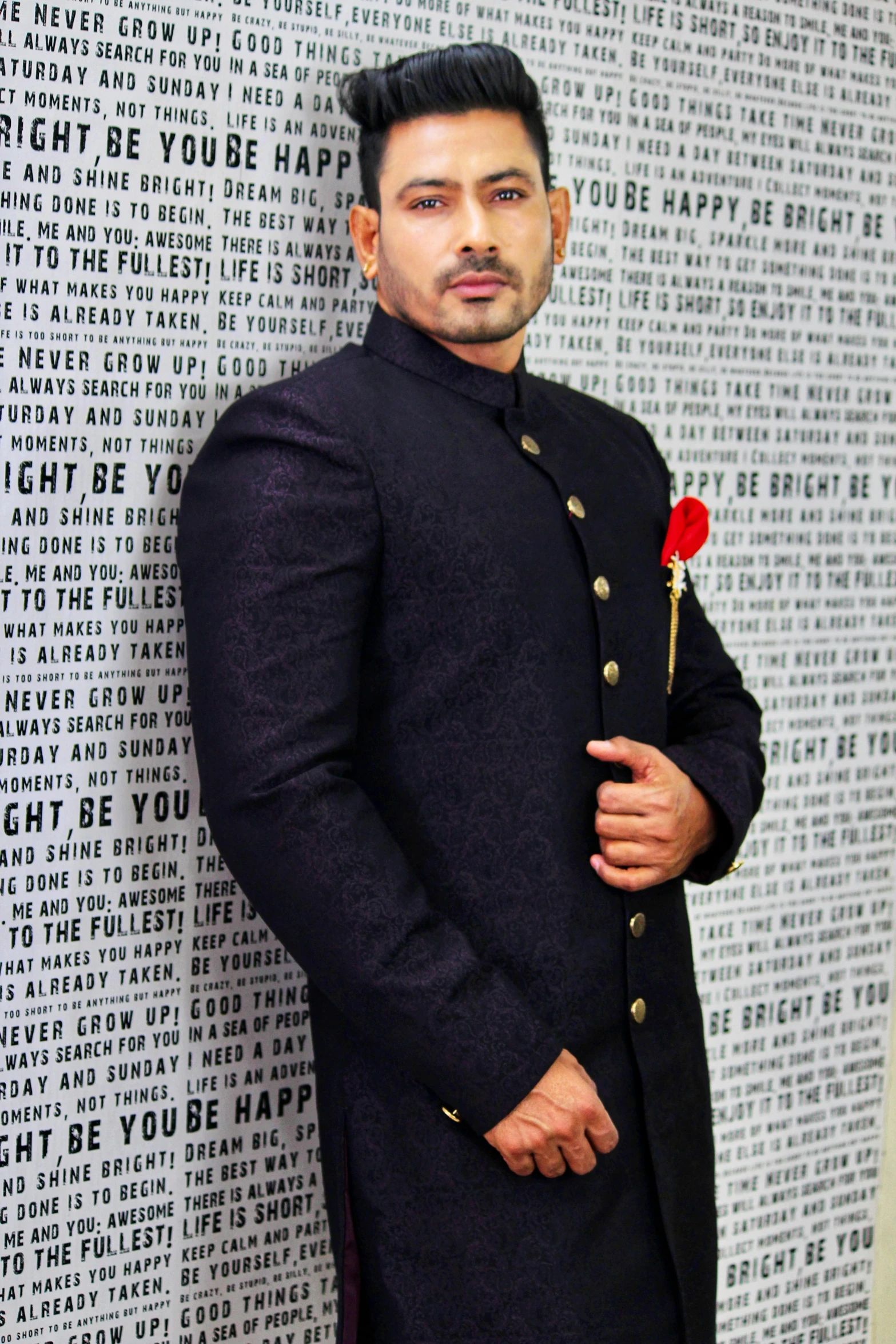 a man standing in front of a wall with a rose in his hand, an album cover, inspired by Saurabh Jethani, wearing a black noble suit, pout, with mustache, masculine appeal high fashion