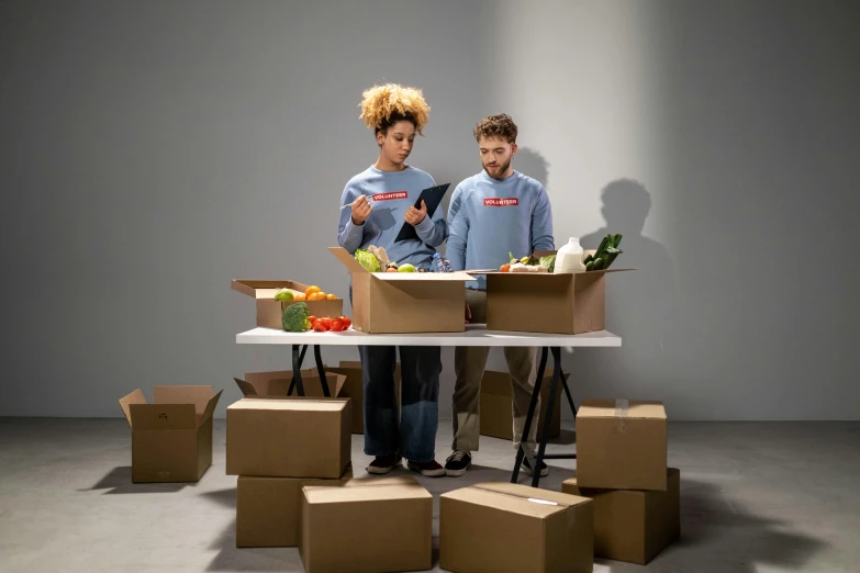 a couple of people standing in front of boxes, on a table, food, profile image