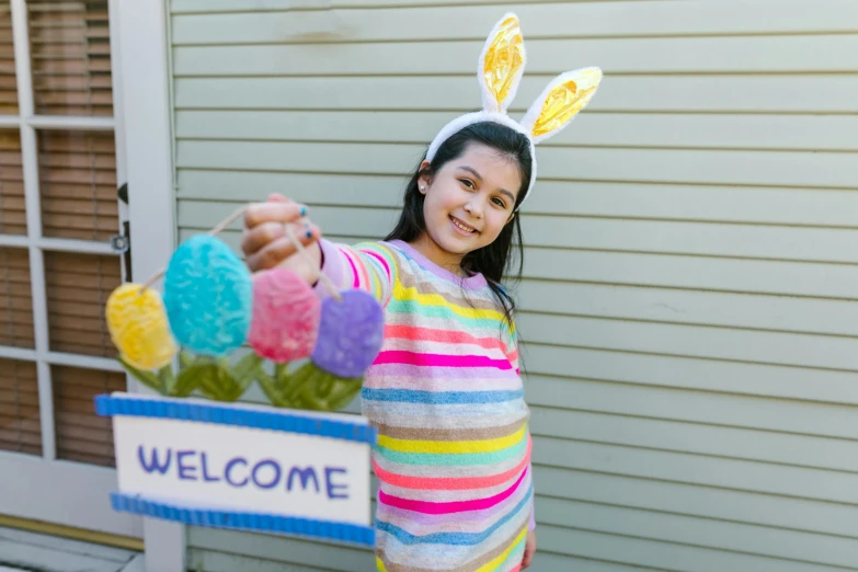 a girl in a bunny costume holding a welcome sign, pexels, candy decorations, a brightly colored, postprocessed, [ cinematic