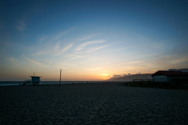 a beach at sunset with a lifeguard tower in the distance, profile image, los angelos, as photograph, image