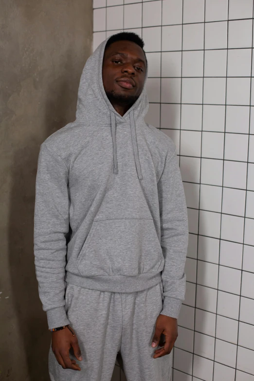 a man standing next to a urinal in a bathroom, an album cover, inspired by Paul Georges, light grey hoodie opened, wearing a track suit, official product image, photo of a model