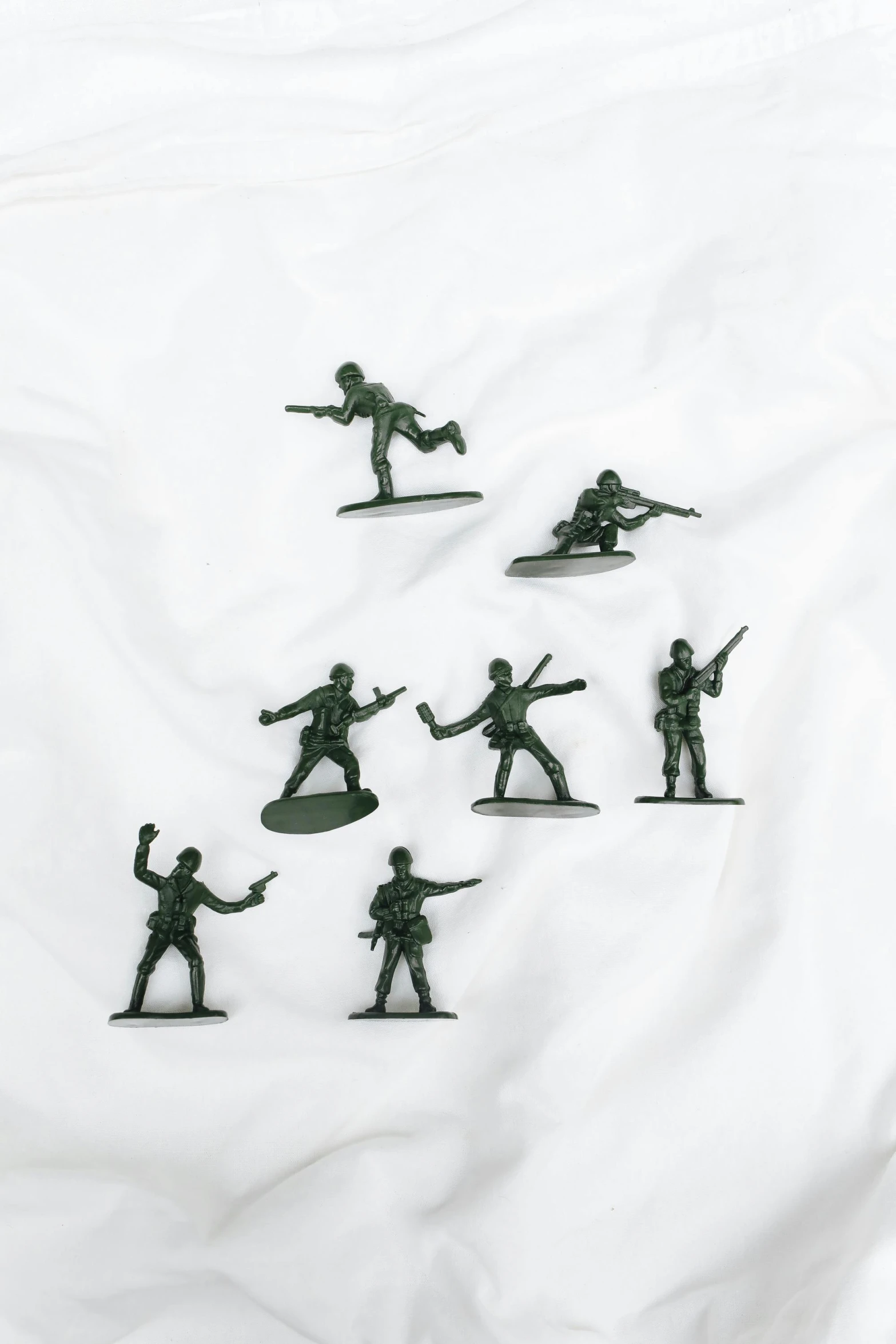 a group of toy soldiers sitting on top of a white sheet, 8 x, olive green, group of seven, plastic toy