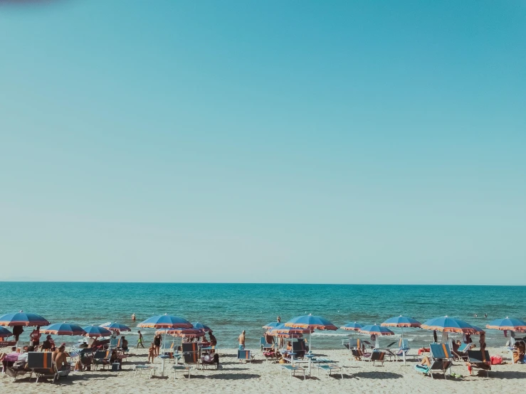 a group of people sitting under umbrellas on a beach, pexels contest winner, clear blue sky, italian beach scene, sparsely populated, unsplash 4k