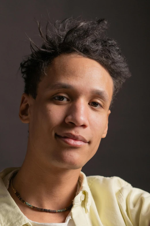 a man in a yellow shirt posing for a picture, by Jacob Toorenvliet, light-brown skin, non-binary, official government photo, curls on top of his head