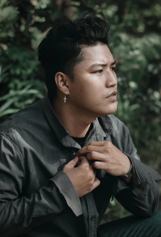 a man in a leather jacket tying his tie, an album cover, inspired by Rudy Siswanto, unsplash, sumatraism, wearing camo, androgynous person, thick jungle, around 1 9 years old