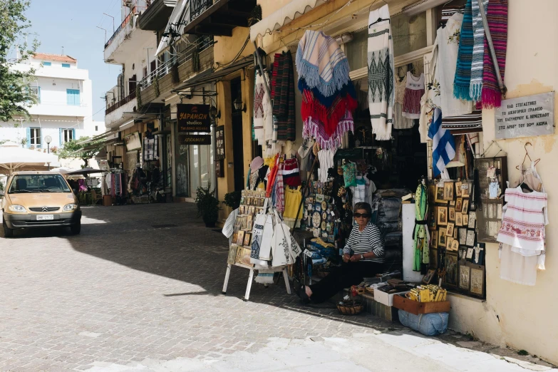 a street scene with a car parked on the side of the road, crafts and souvenirs, profile image, greek style, market stalls