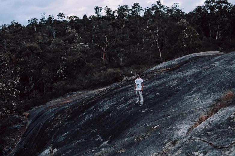 a man standing on top of a large rock, by Lee Loughridge, happening, straya, people walking around, lachlan bailey, lo-fi