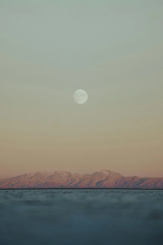 a full moon in the sky over a body of water, an album cover, unsplash, romanticism, distant mountain range, pale beige sky, mojave desert, today\'s featured photograph 4k