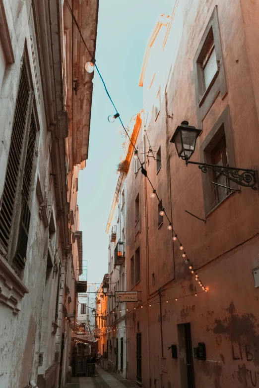 a narrow street in an old european city, unsplash contest winner, renaissance, wires and lights, pastel hues, brown, mediterranean