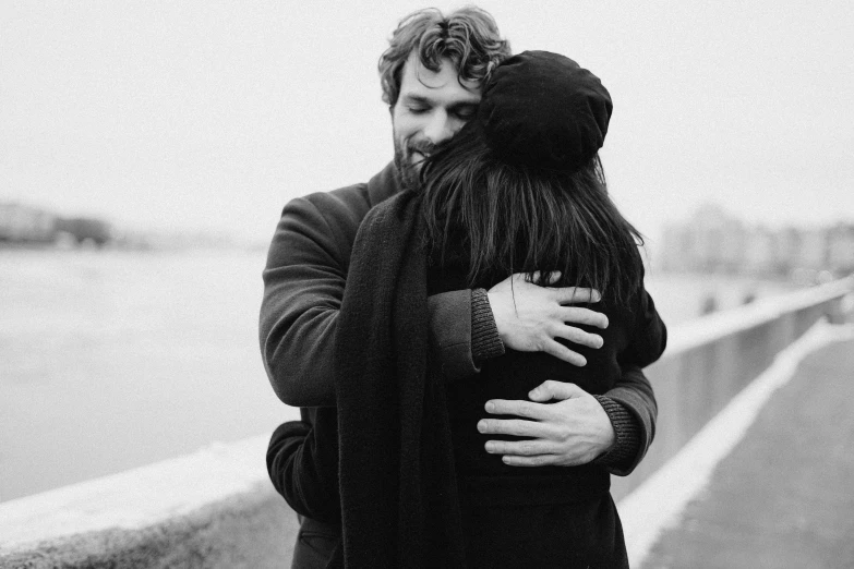 a black and white photo of a man hugging a woman, a black and white photo, by Matija Jama, pexels, ffffound, happy friend, a cold, holding