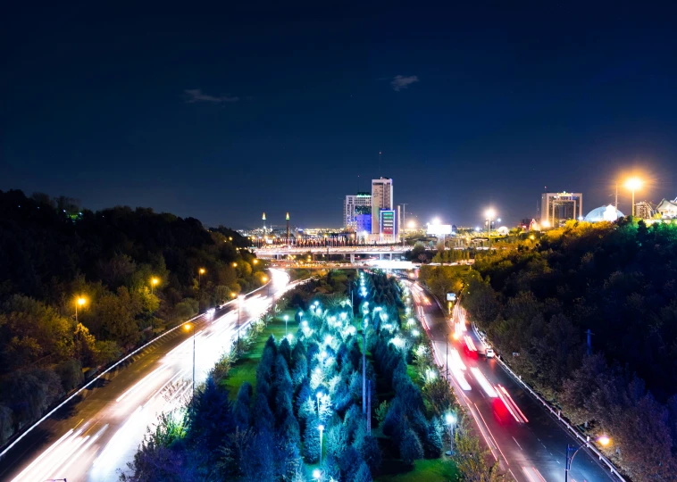 an aerial view of a city at night, by Micha Klein, unsplash contest winner, hurufiyya, city lights made of lush trees, tallinn, light trails, coventry city centre