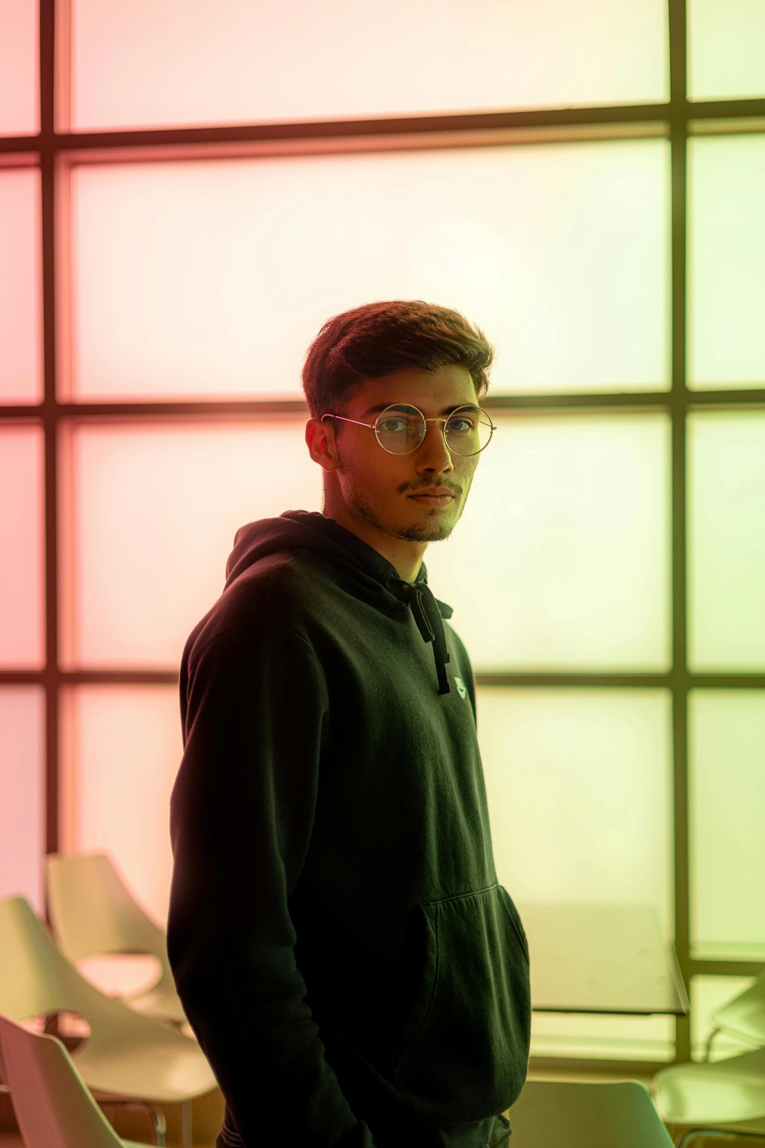 a man standing in front of a colorful wall, hyperrealism, mia khalifa, black hoodie techie, studio backlight, androgynous person