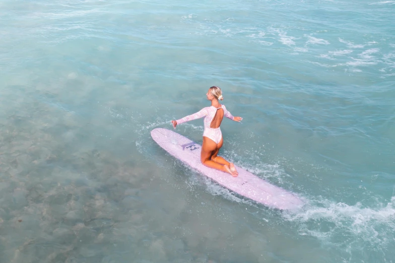 a woman riding a surfboard on top of a body of water, purple water, pink white turquoise, sea foam, blonde