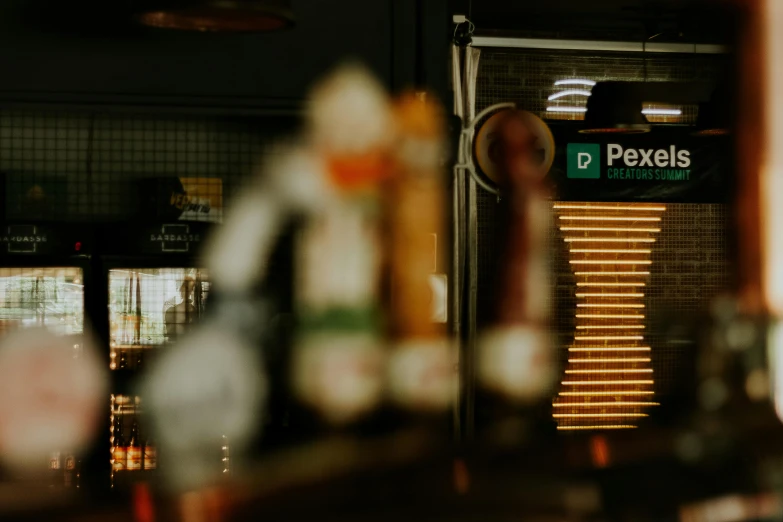 a bunch of beer bottles sitting on top of a counter, a tilt shift photo, by Matteo Pérez, pexels contest winner, photorealism, arcade cabinet in background, drinking coffee at central perk, small nixie tubes, the phoenix