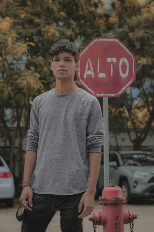 a man standing next to a red fire hydrant, an album cover, by Alejandro Obregón, pexels contest winner, teenage boy, stop sign, proud serious expression, rated t for teen