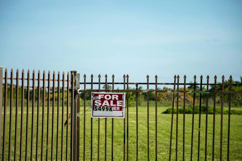 a for sale sign in front of a fence, unsplash, realism, joel sternfeld, kicking a florida mansion, field, getty images