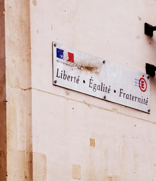 a street sign on the side of a building, by Raphaël Collin, pexels, figuration libre, french revolution, illegible, an intricate, patriotic