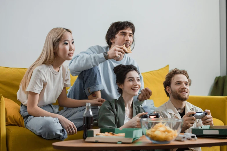 a group of people sitting on top of a yellow couch, a cartoon, trending on pexels, renaissance, eating chips and watching tv, aussie baristas, gaming table, college students