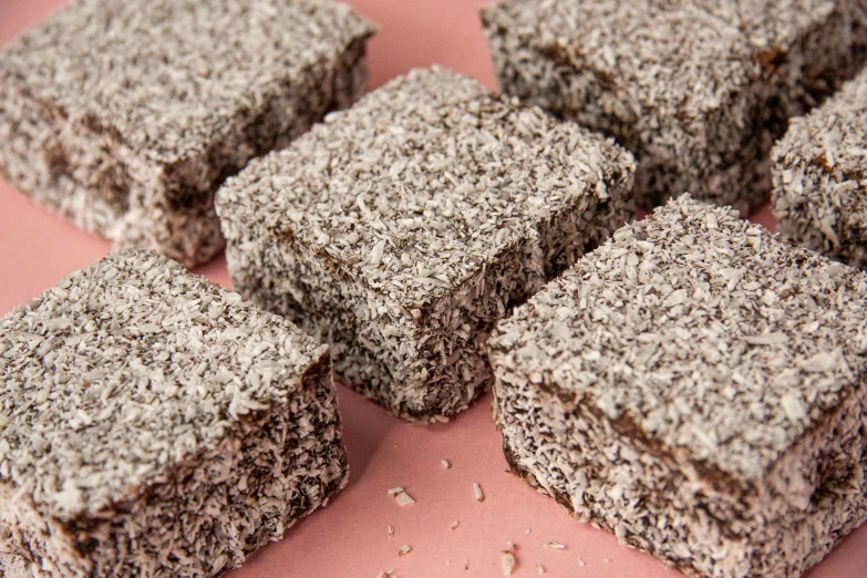 a bunch of brownies sitting on top of a pink surface, hurufiyya, grey, strong eggshell texture, detailed product image, medium-shot