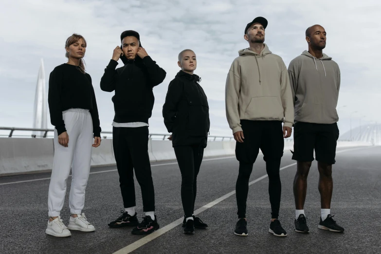 a group of people standing on the side of a road, pexels contest winner, antipodeans, wearing a track suit, photoshoot for skincare brand, running sequence, black clothing