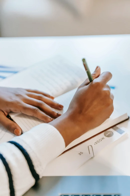 a person sitting at a table writing on a piece of paper, sleek hands, educational supplies, thumbnail, high quality image