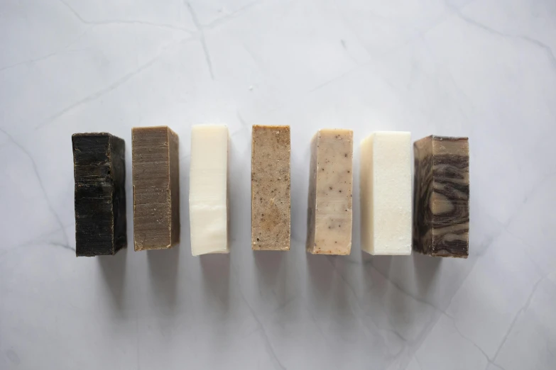 a row of soap bars sitting on top of a counter, by Emma Andijewska, dark sienna and white, group of seven, on a pale background, thumbnail