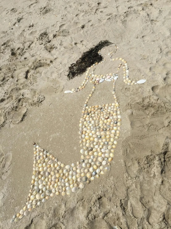 a drawing of a mermaid made out of seashells on the beach, land art, 2019 trending photo