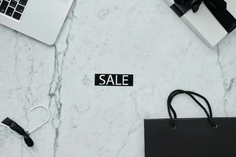 a black bag sitting on top of a table next to a laptop, trending on pexels, visual art, square sticker, sales, marble background, black + white