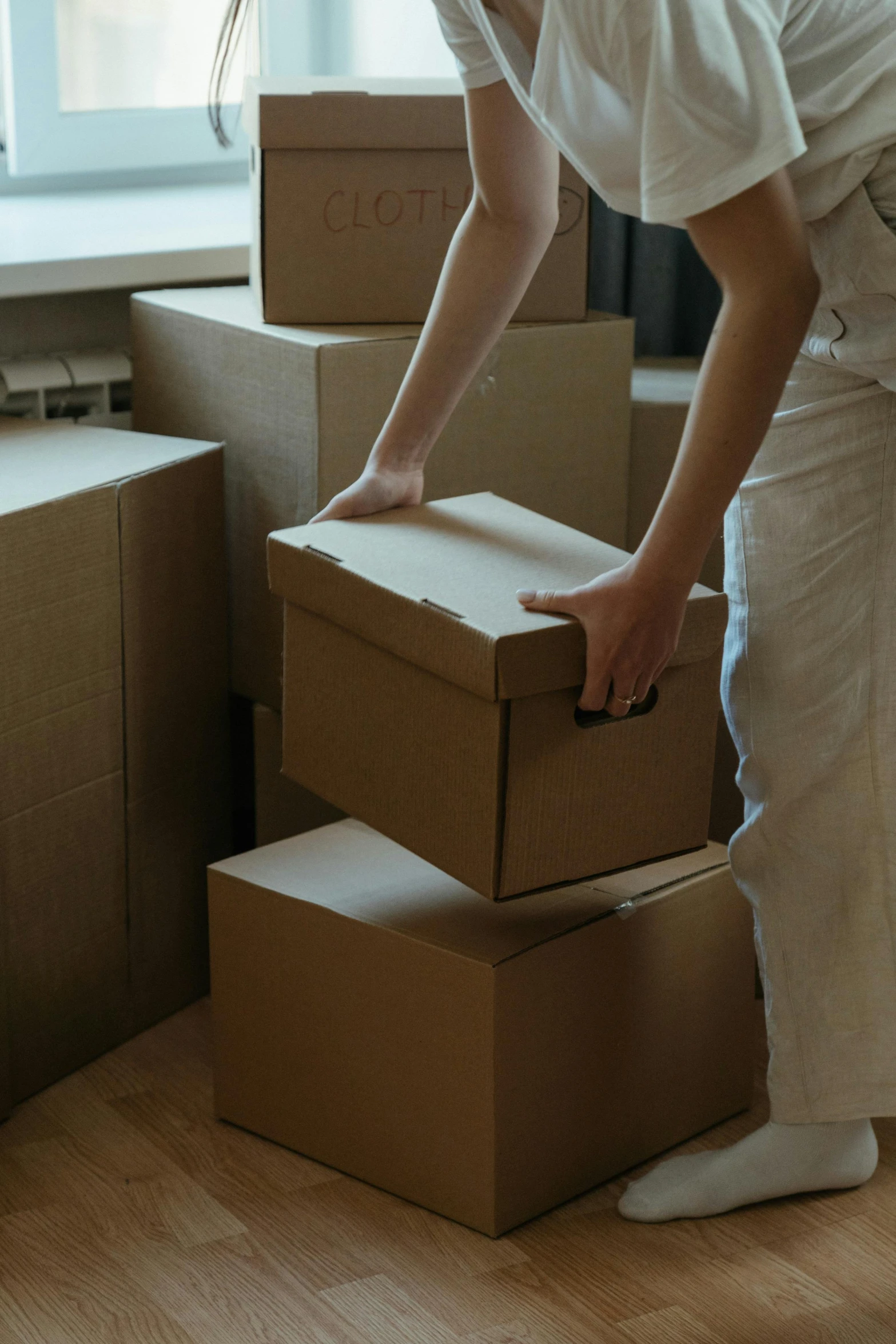 a man standing next to a stack of boxes, pexels contest winner, hurufiyya, bending down slightly, photo of a woman, sydney, opening