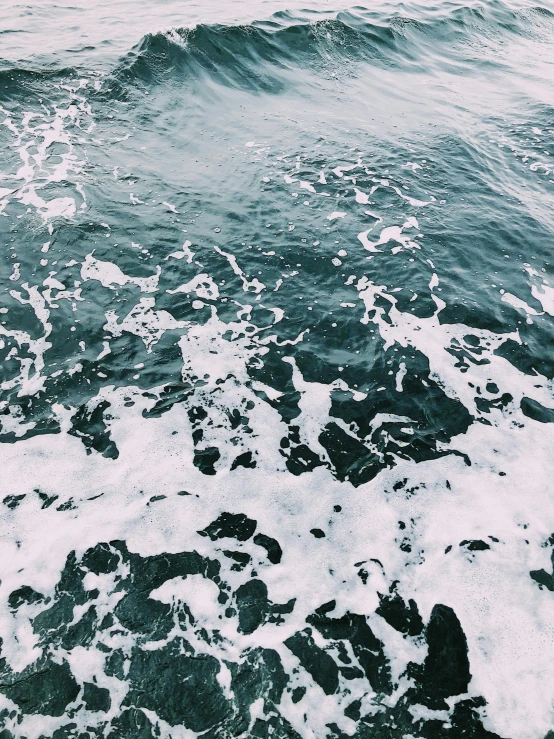 a person riding a surfboard on top of a wave, an album cover, trending on unsplash, water texture, low quality photo, sea foam, photo taken from a boat