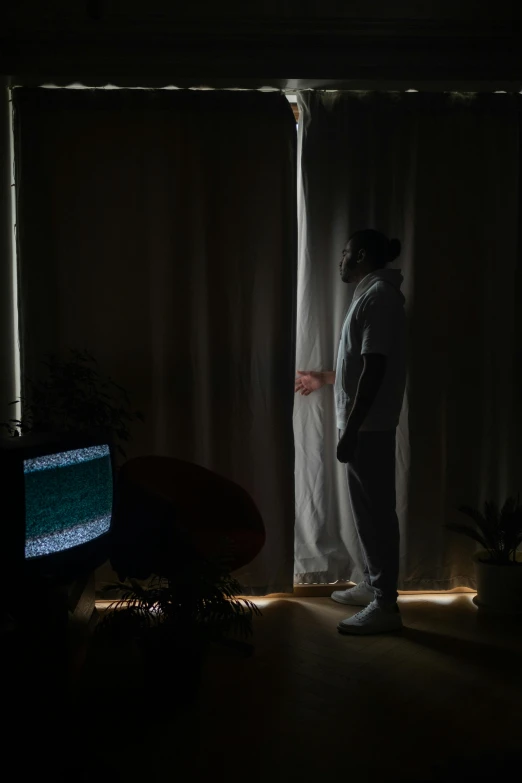 a man standing in front of a window in a dark room, watching tv, chillhop, still photograph, set photo