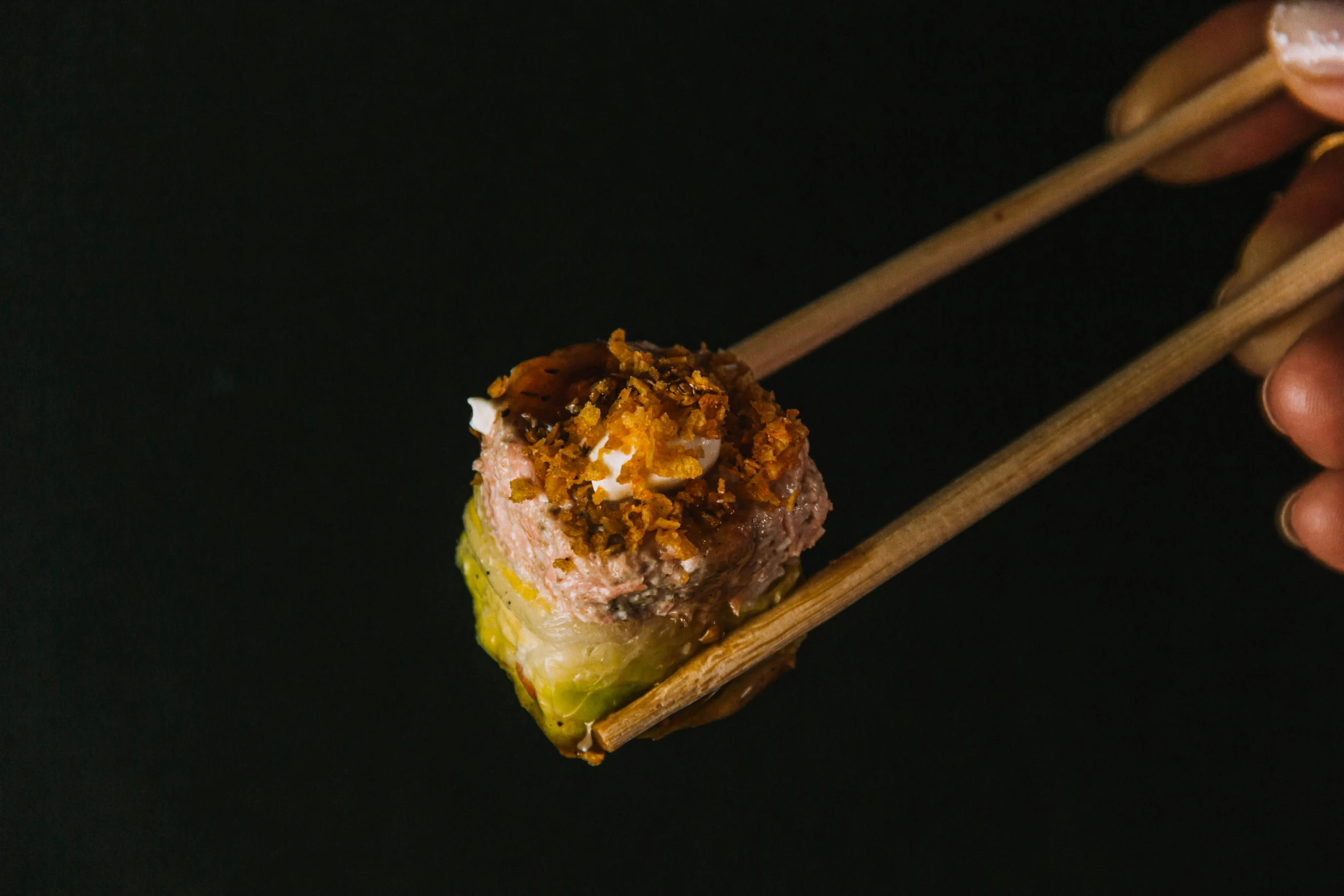 a person holding chopsticks over a piece of food, a picture, mingei, with a black background, meat and lichens, grilled artichoke, pov photo