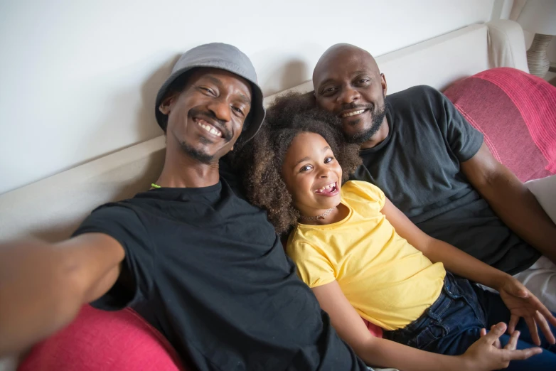 a group of people sitting on top of a couch, by Samuel Washington Weis, pexels, figuration libre, caring fatherly wide forehead, adut akech, portrait of family of three, snapchat photo