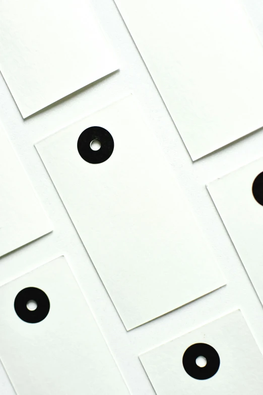 a number of black buttons on a white surface, an album cover, by Adam Rex, unsplash, minimalism, card template, enso, sheet paper, 9 9 designs