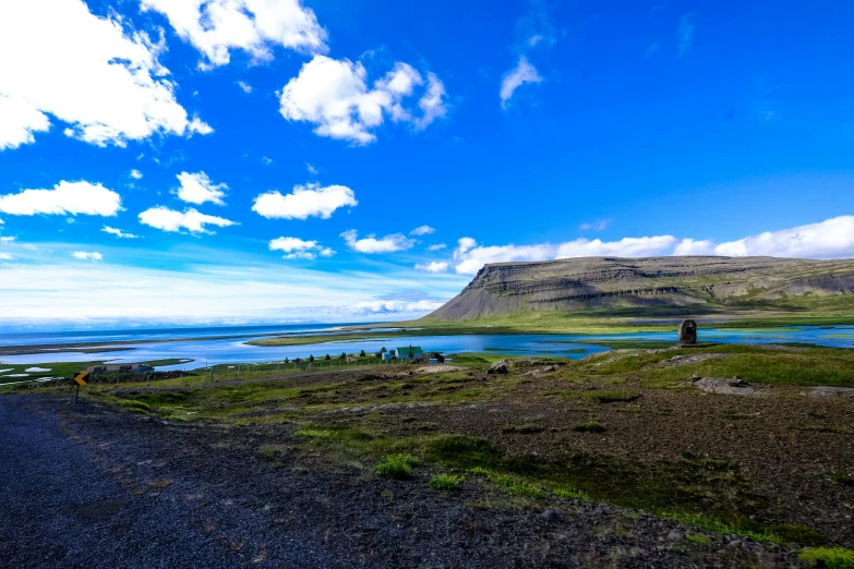 a car parked on the side of a road next to a body of water, by Julia Pishtar, pexels contest winner, hurufiyya, icelandic landscape, blue sky and green grassland, devils horns, background image