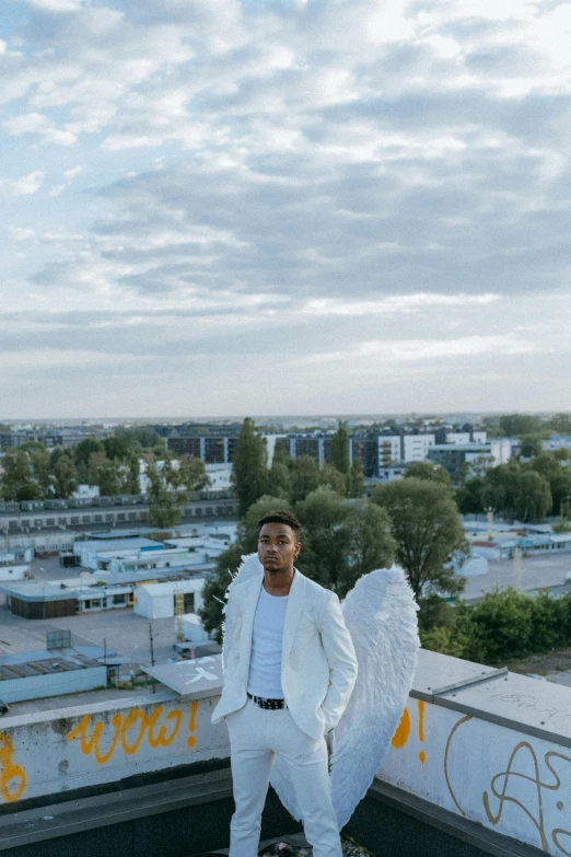 a man in a white suit standing on a roof, an album cover, by Jacob Toorenvliet, pexels contest winner, happening, young wan angel, donald glover, wide open wings, photo taken on a nikon