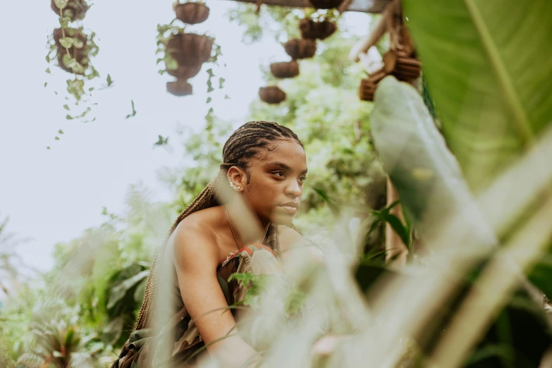 a woman sitting on top of a lush green field, by Daniel Lieske, pexels contest winner, afrofuturism, standing in a botanical garden, girl with plaits, plants inside cave, medium close up portrait